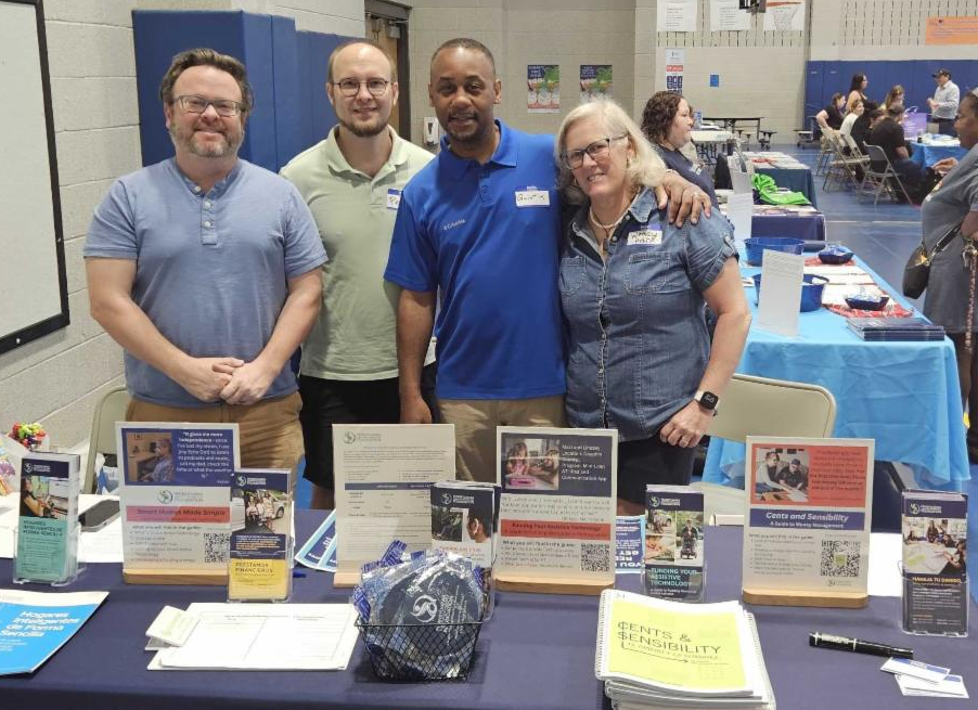 There are four PATF employees standing behind our resource table at an event.