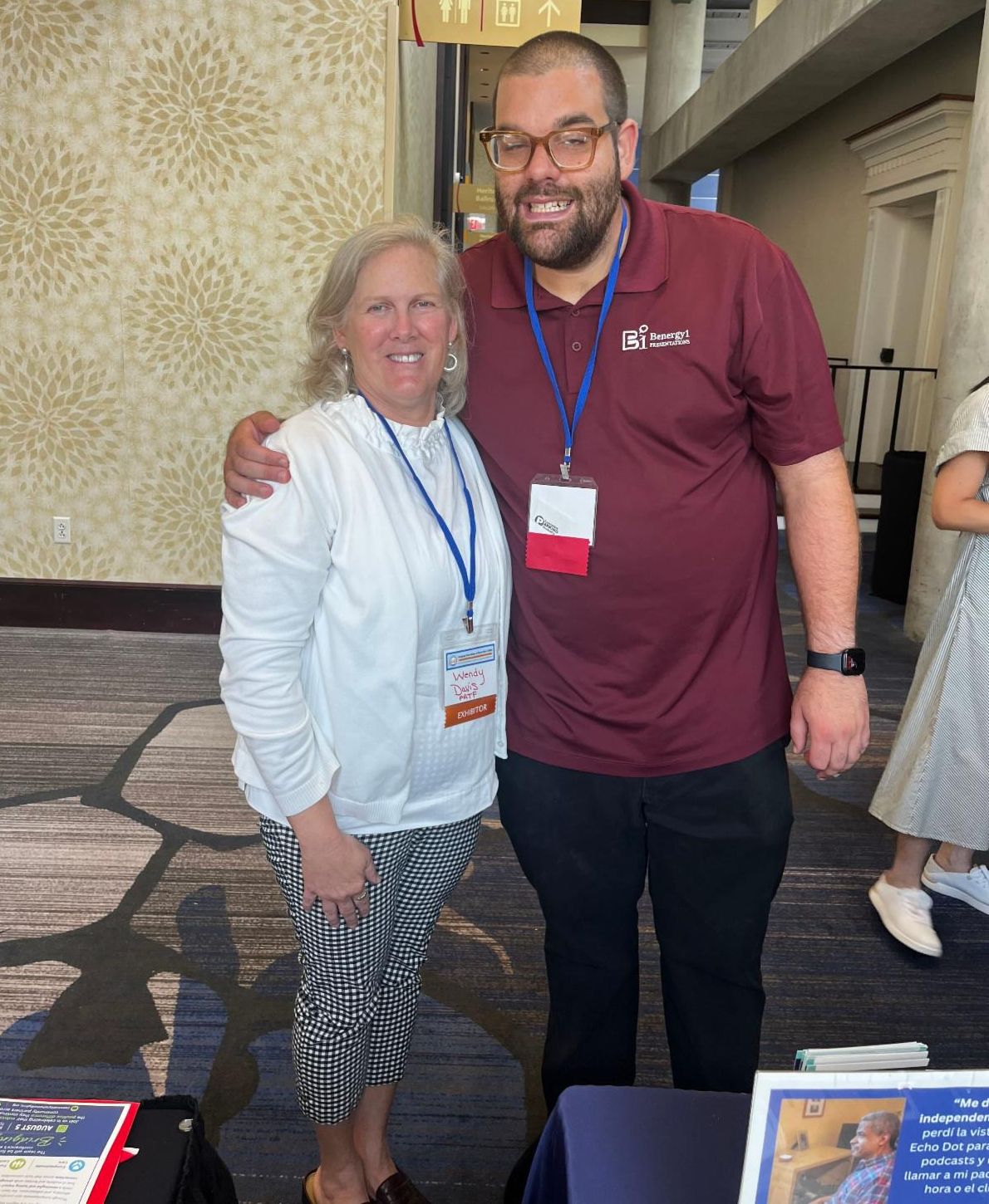 Wendy is wearing a white long sleeve shirt and black and white checkered pants. She is standing next to Ben who is wearing a maroon short sleeve shirt and black pants.