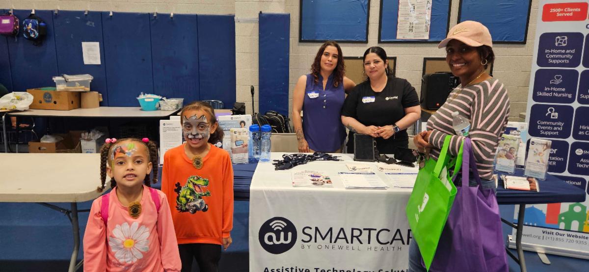 Two young girls and three women standing near a table.