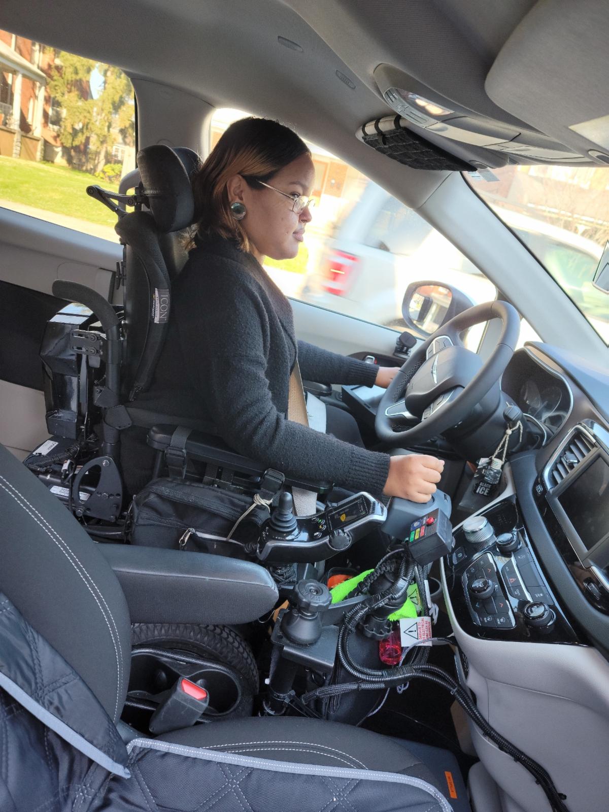 Kathia is in the driver's seat of her adapted vehicle.