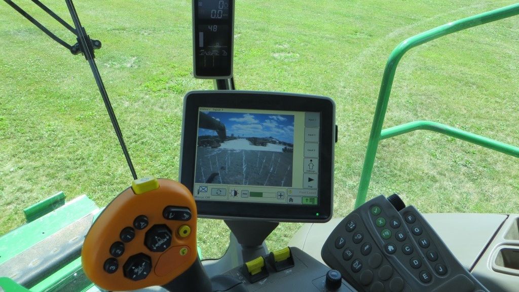 Cab camera screen inside a harvester shows a view of the field behind the vehicle.