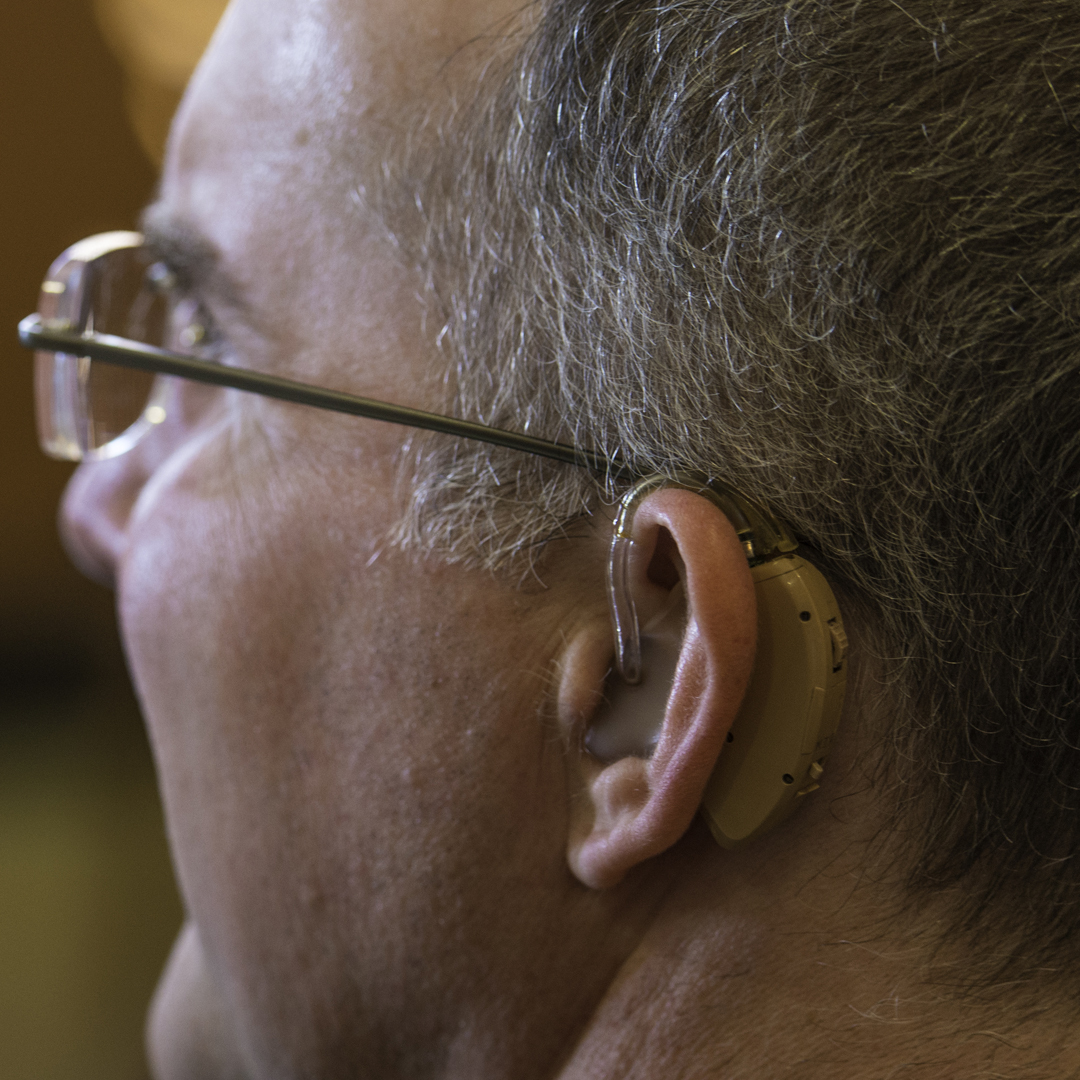 A white man wears a hearing aid