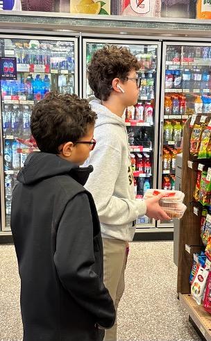 Two young boys stand in an aisle in a grocery store.