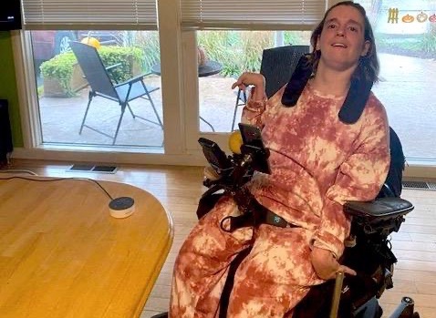 Alexa is on the right of the photo in a wheelchair with orange and cream-colored sweatsuit