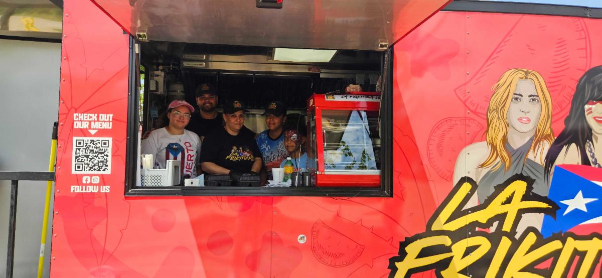A red food truck with five people standing inside.