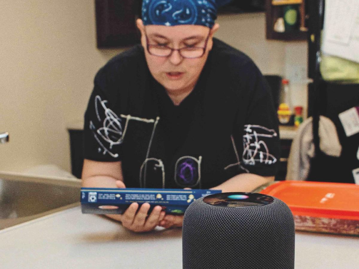 A person looks at a spaghetti box and speaks to an Apple HomePod.