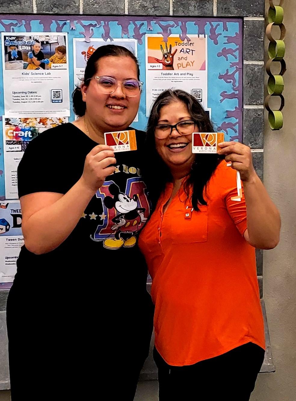 Two students hold up their new library cards