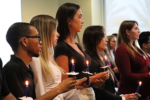 Students standing during a candlelit induction ceremony
