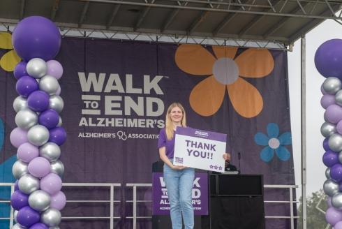 Nik Lampe on stage holding a thank you sign