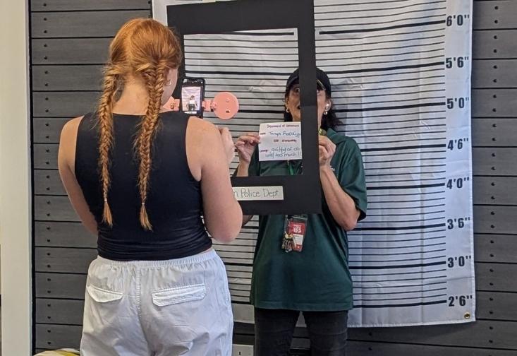 Students take photos in front of a mock mug shot