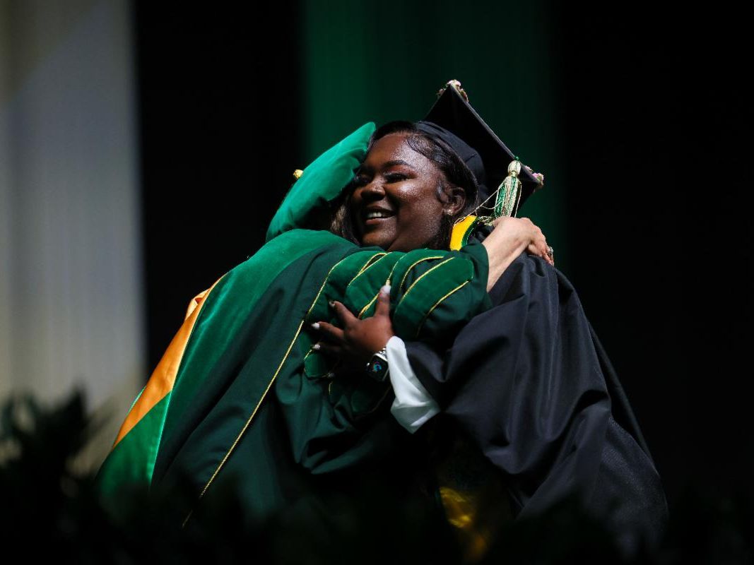 A graduate student hugging a faculty member