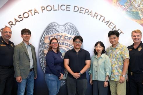 Researchers stand in front of the Sarasota Police Department logo and American Flag