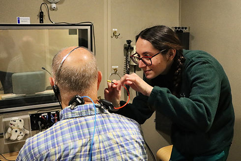 An audiology student conducts a hearing exam on a patient