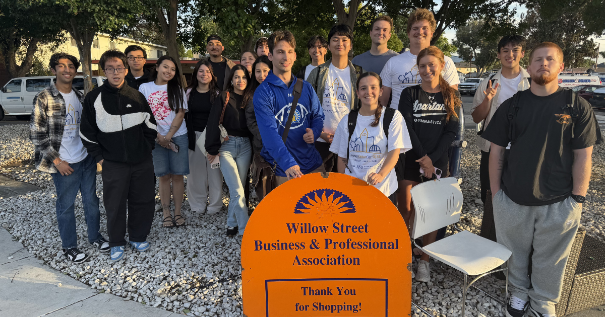 20 SJSU students assembled around an orange sign reading "Willow Street Business & Professional Association"