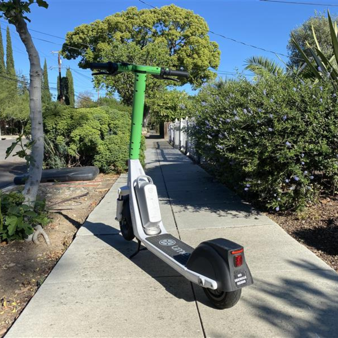 Lime Scooter in the middle of a sidewalk.