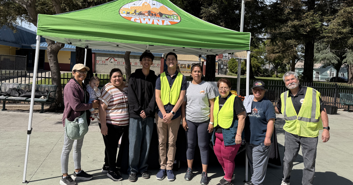 Councilmember Anthony Tordillos and 8 members of the Guadalupe Washington Neighborhood Association assembled under a green tent with the GWNA logo.