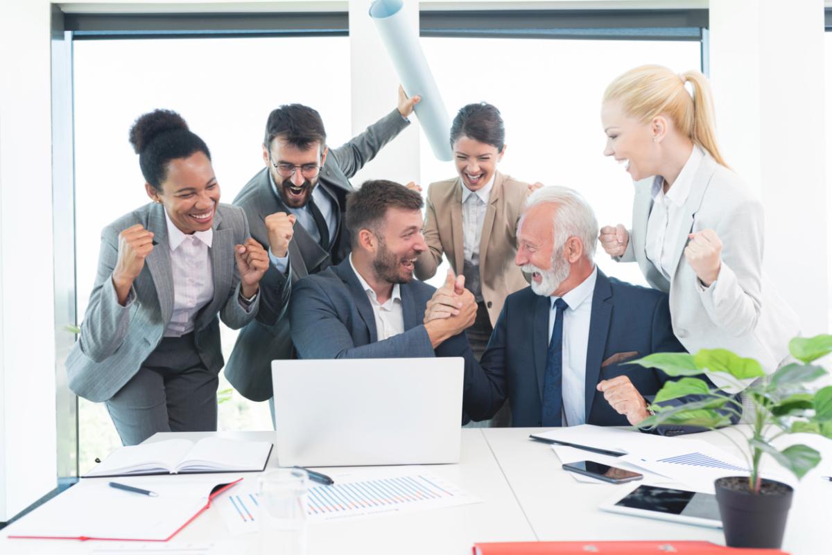 business people celebrating in front of laptop