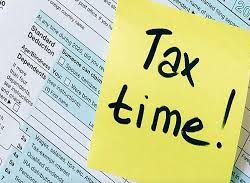 Taxes due clip art. Shows a yellow sticky note with Tax Time written in Sharpie marker laying on top of IRS forms