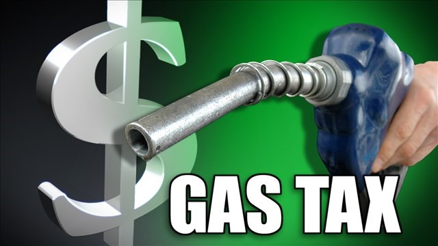 Dollar sign gas nozzle with blue handle that a left hand is clutching with the words gas tax below