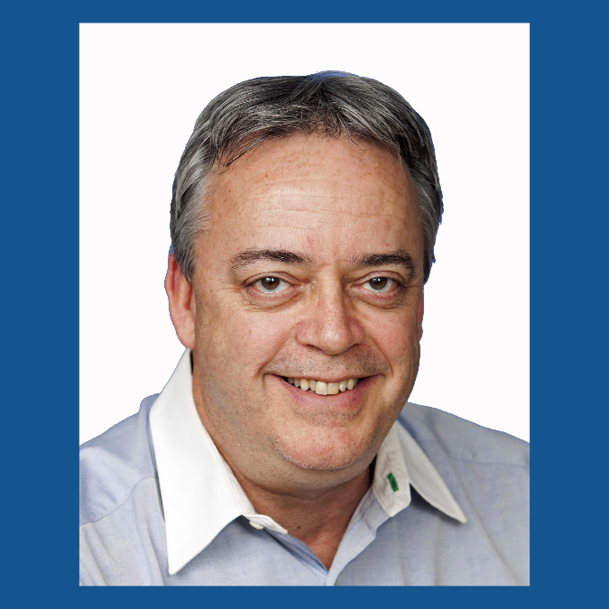 a man smiling in a headshot with a grey sweater and a white collared shirt