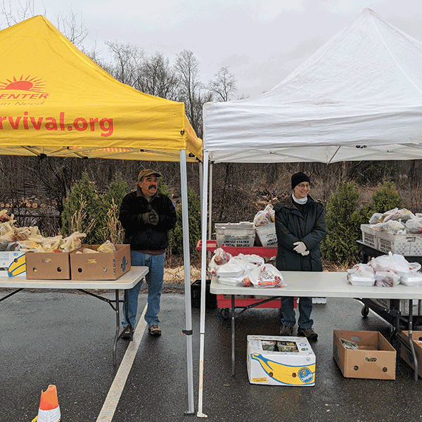Tent in parking lot with volunteers serving lunch_ produce and bread