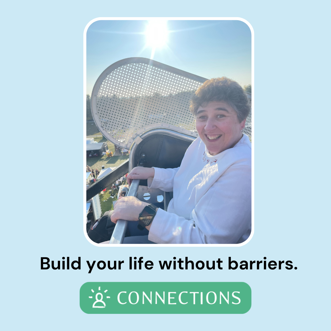A smiling woman in a seat at the top of a Ferris wheel 