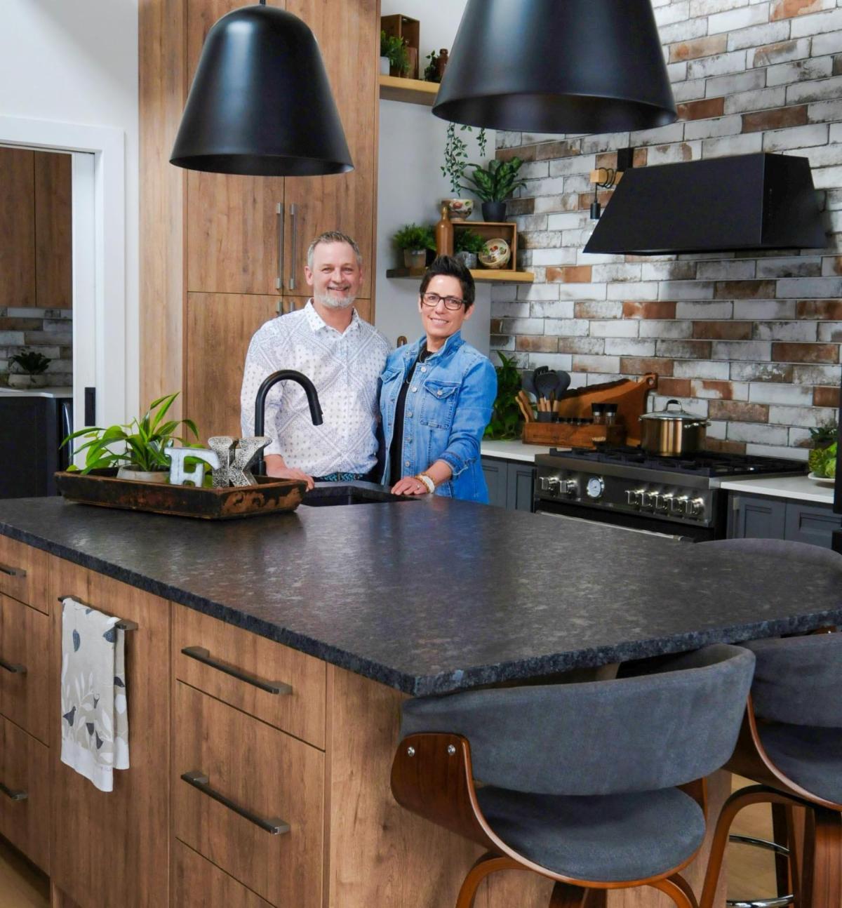 A man Ed and a woman Kelly smile while standing in a kitchen showroom