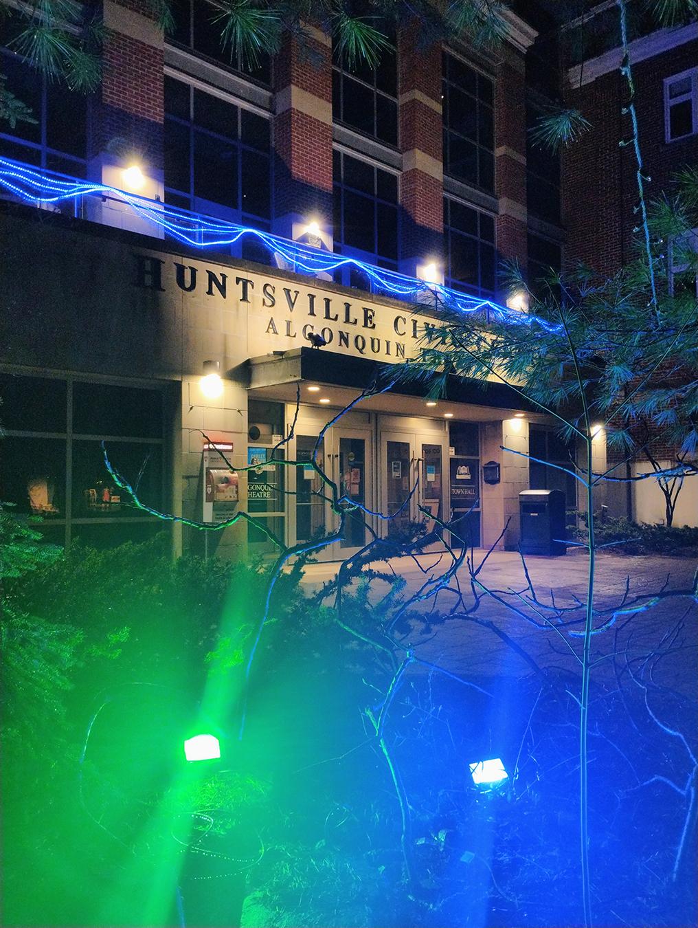 Huntsville Civic Square lit at night with blue and green floodlights