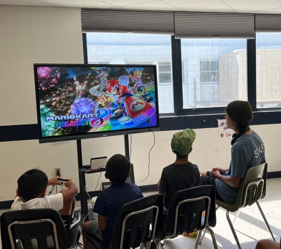 Group of 4 children in front of a television and playing the video game Mario Kart