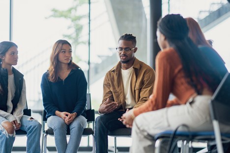 Meeting attendees sitting in a circle listening to speaker