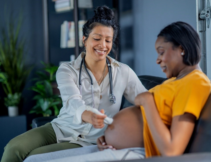 Midwife holding stethoscope to pregnant womans abdomen