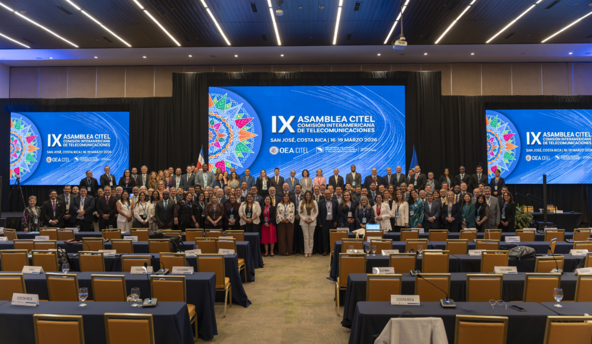 Participantes de la IX Asamblea de la CITEL se reúnen para una foto grupal. Todos están de pie en tres filas, con los más altos al fondo.
