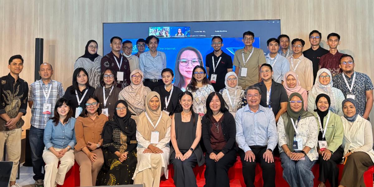 Group photo showing ICANN and PANDI representatives, including one on Zoom placed on a screen in the back.