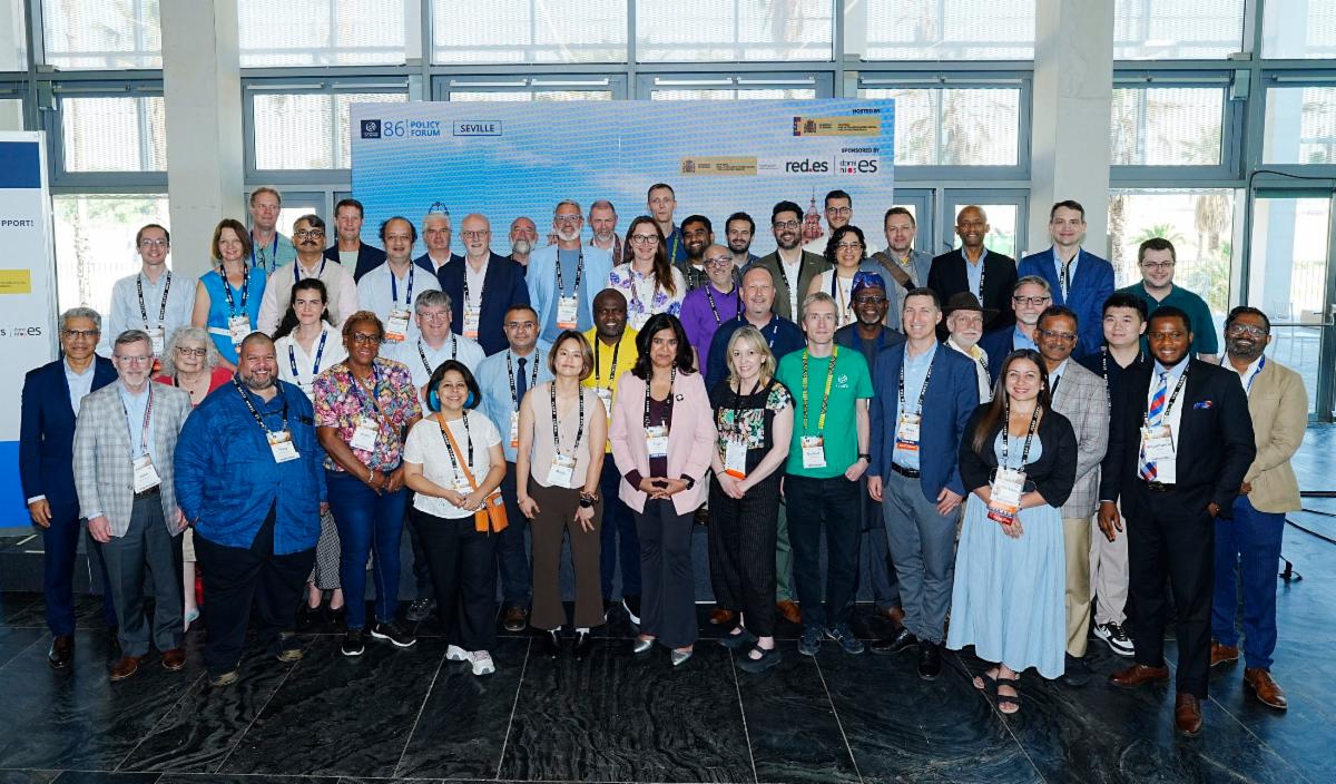 A group of ICANN86 attendees, including some ICANN executives and staff, gather for a group photo in front of an ICANN-branded photo backdrop at the Community Networking Reception that took place at the ICANN86 Policy Forum.