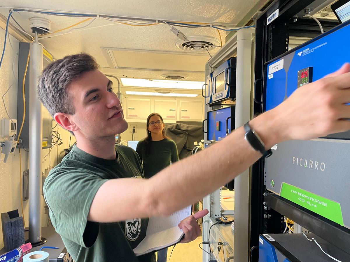 CSU graduate students Jared Stickney and Dani Guevara check readings on air quality instruments at the Fort Collins-West air quality measurement station at CSU’s Christman Field. Photo by Jenn Fields for the Regional Air Quality Council.
