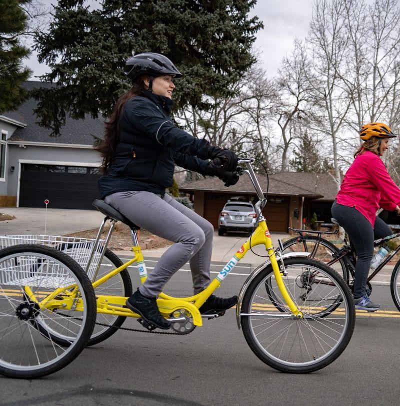 A woman riding an adaptive trike on the street. 