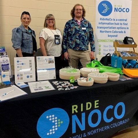 Three NFRMPO Staff members standing behind a booth at an outreach event. 