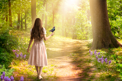 Lady girl with long hair in dress with bird in hand walking in fantasy enchanted fairy tale spring forest with blooming flowers and sun rays_ mysterious road goes through trees in magical elvish wood