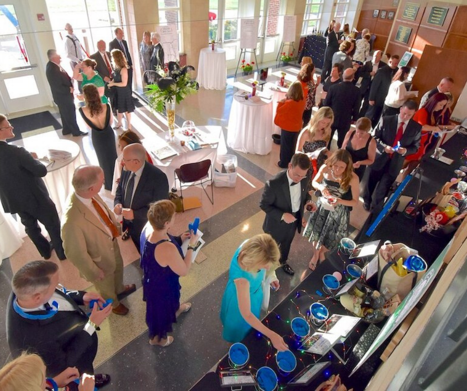 People dressed formally standing and talking together in a room.