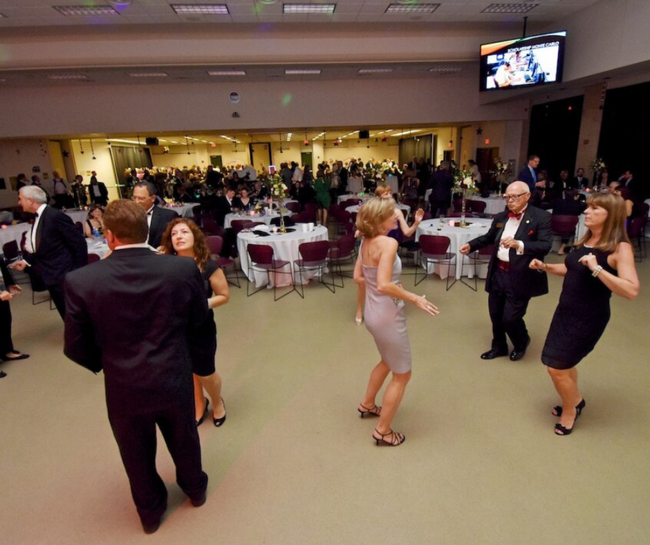 People dressed formally dancing together in a large event room.