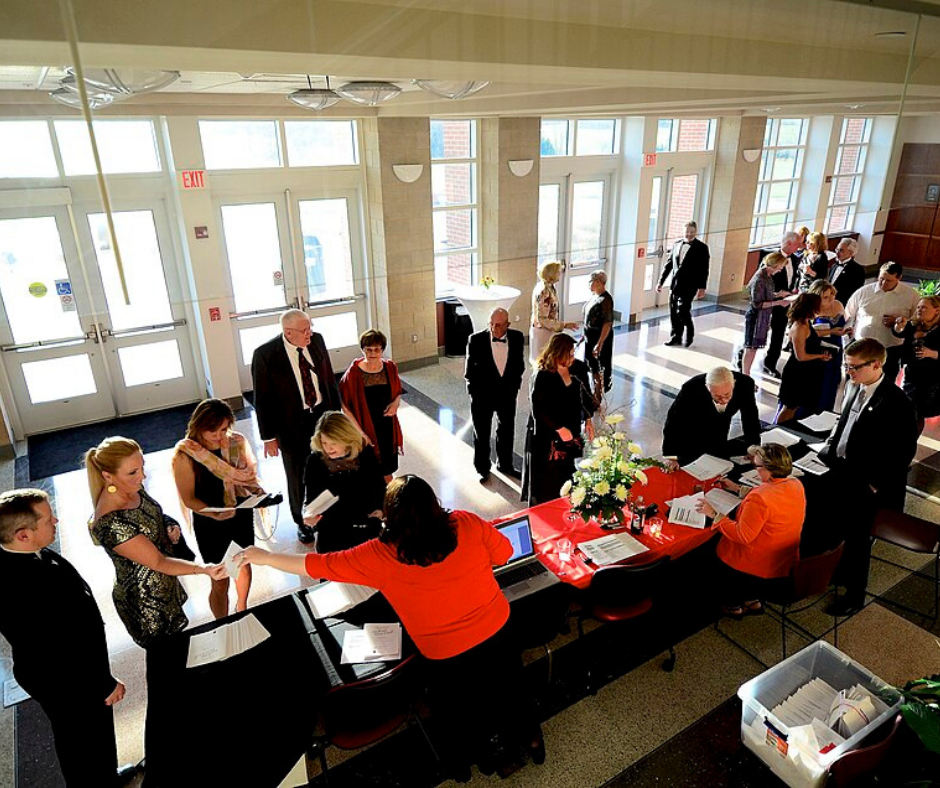 People checking in at a registration table for a formal event.