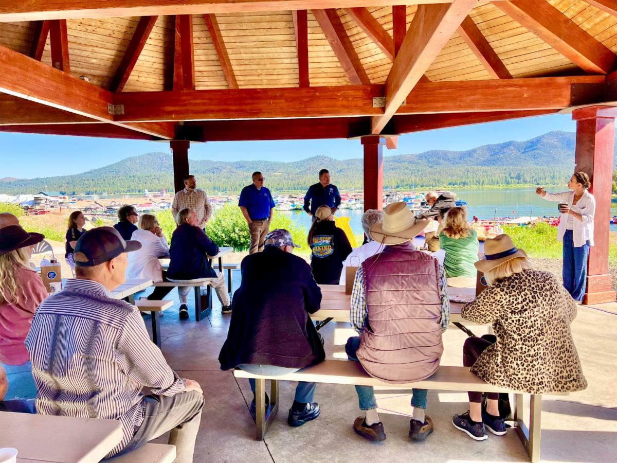Image of a crowd gathered under the gazebo at Veteran's Park in Big Bear Lake as Mayor Melnick, City Manager Erik Sund, Assistant City Manager Sean Sullivan and Economic Development Manager Kelly Tinker provide updates.