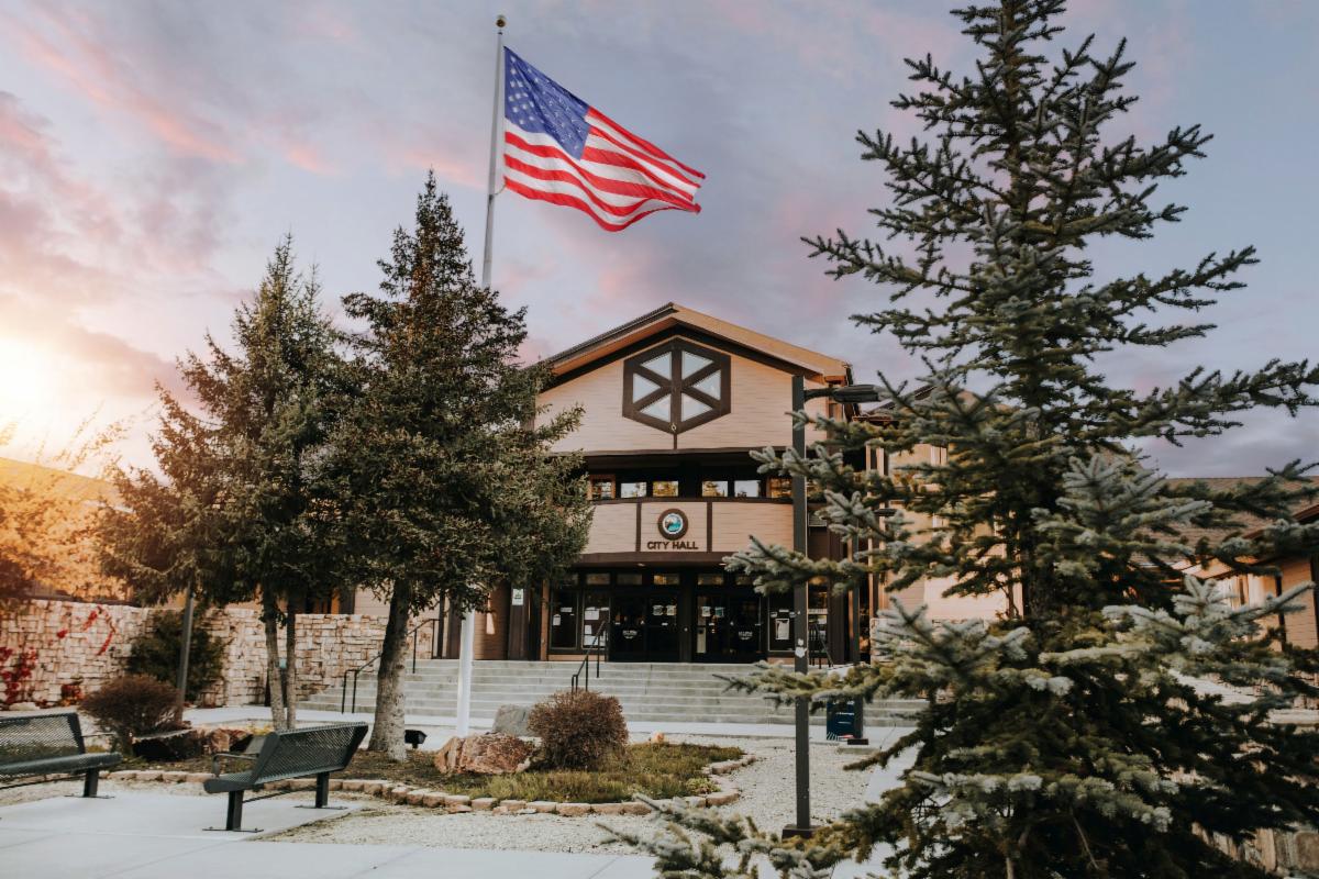 Image of Big Bear Lake City Hall at sunset with an American flag waving