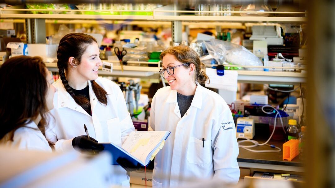 UCSF Assistant Professor in Pharmaceutical Chemistry Balyn Zaro, PhD, right, speaks with graduate students Regan Volk, center, and Sara Warrington, left, in her lab at UCSF’s Mission Bay campus on Tuesday, Jan 17, 2023. Her laboratory uses chemical biology to study how protein expression changes during aging, disease, and infection.