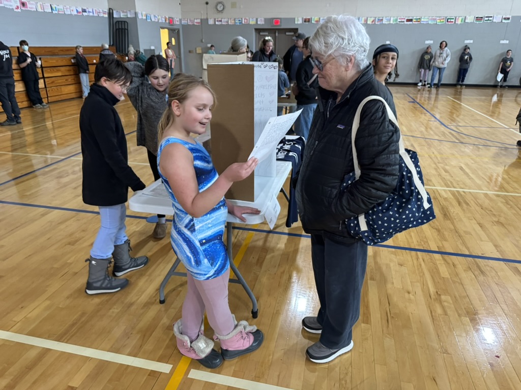elementary student reading about her career to an adult