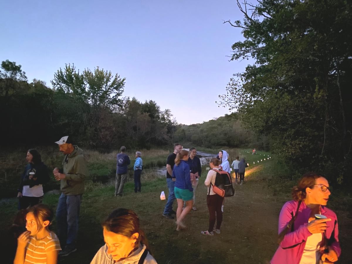 people walking on a path by the river at dusk