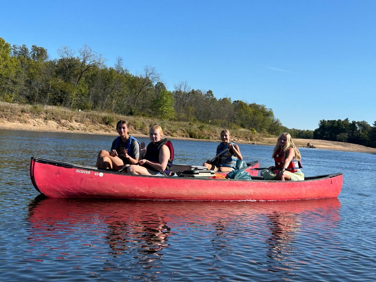 4 teenage girls in a red canoe on a river