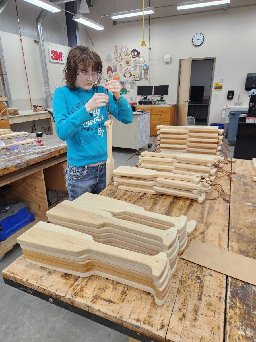 student finishing wooden paddle