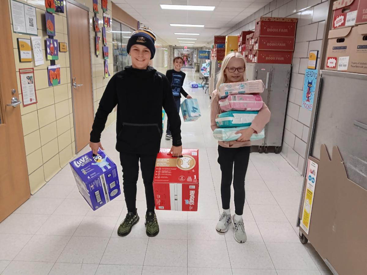 a boy and girl carrying diapers in the school hallway