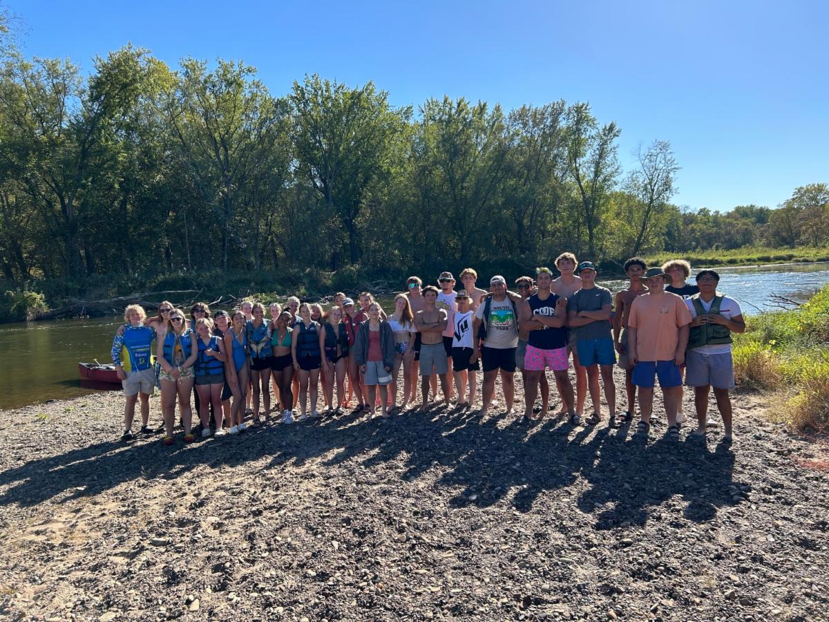 teenagers standing on a beach in front of a river